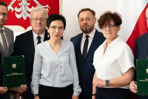 Sześć osób pozuje do zdjęcia, trzymając zielone teczki z napisem "Minister Rolnictwa i Rozwoju Wsi".