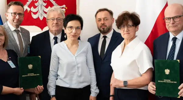 Sześć osób pozuje do zdjęcia, trzymając zielone teczki z napisem "Minister Rolnictwa i Rozwoju Wsi".