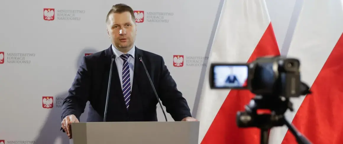 Mężczyzna w garniturze przemawia przy mównicy na tle flagi Polski i logo Ministerstwa Edukacji Narodowej.