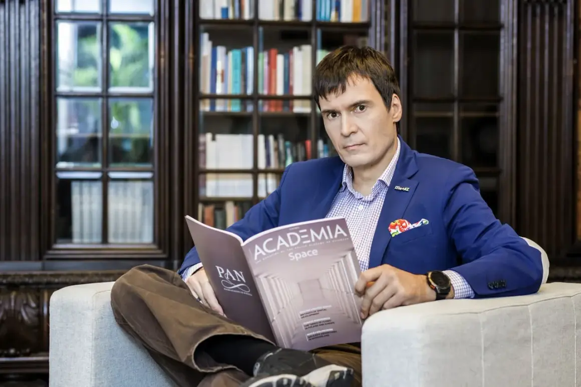 Mężczyzna w niebieskiej marynarce siedzi w fotelu i czyta magazyn "Academia Space".