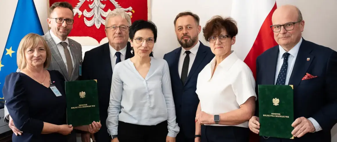 Sześć osób pozuje do zdjęcia, trzymając zielone teczki z napisem "Minister Rolnictwa i Rozwoju Wsi".