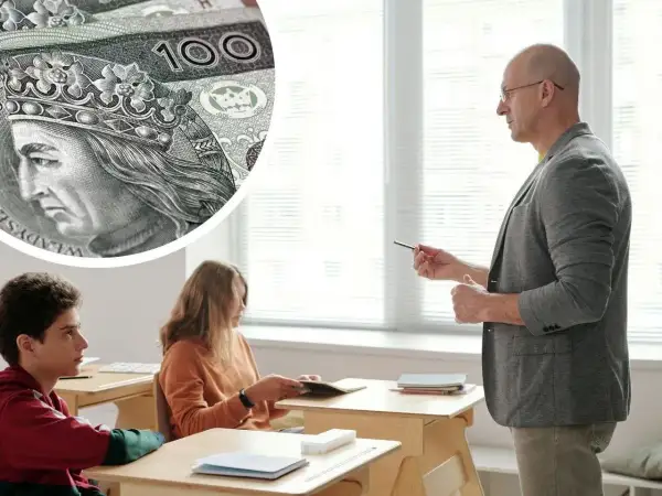 Zbliżenie na polskie banknoty 100 zł i nauczyciela prowadzącego lekcję dla uczniów.