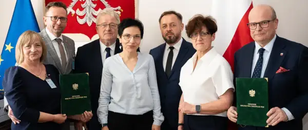 Sześć osób pozuje do zdjęcia, trzymając zielone teczki z napisem "Minister Rolnictwa i Rozwoju Wsi".